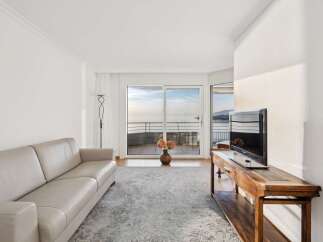 Experience breathtaking ocean views from this elegant living room, featuring a plush leather sofa and a large flat-screen TV.