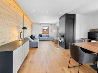 Experience modern living in this beautifully appointed living space, featuring a sleek grey sectional sofa complemented by a striking wood-paneled accent wall.