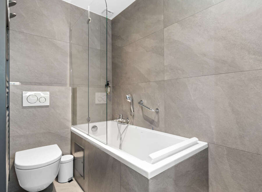 Experience modern luxury in this sleek bathroom, featuring a deep soaking tub perfect for relaxation and a wall-mounted toilet with a dual-flush system for efficiency.
