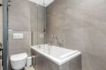 Experience modern luxury in this sleek bathroom, featuring a deep soaking tub perfect for relaxation and a wall-mounted toilet with a dual-flush system for efficiency.
