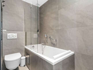 Experience modern luxury in this sleek bathroom, featuring a deep soaking tub perfect for relaxation and a wall-mounted toilet with a dual-flush system for efficiency.