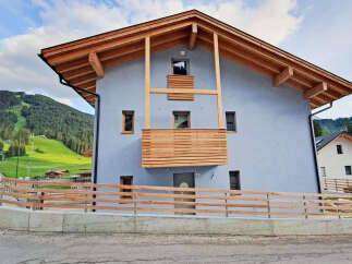 Experience modern alpine living in this stunning new construction, featuring a light blue stucco exterior and a striking wooden-beamed roofline.