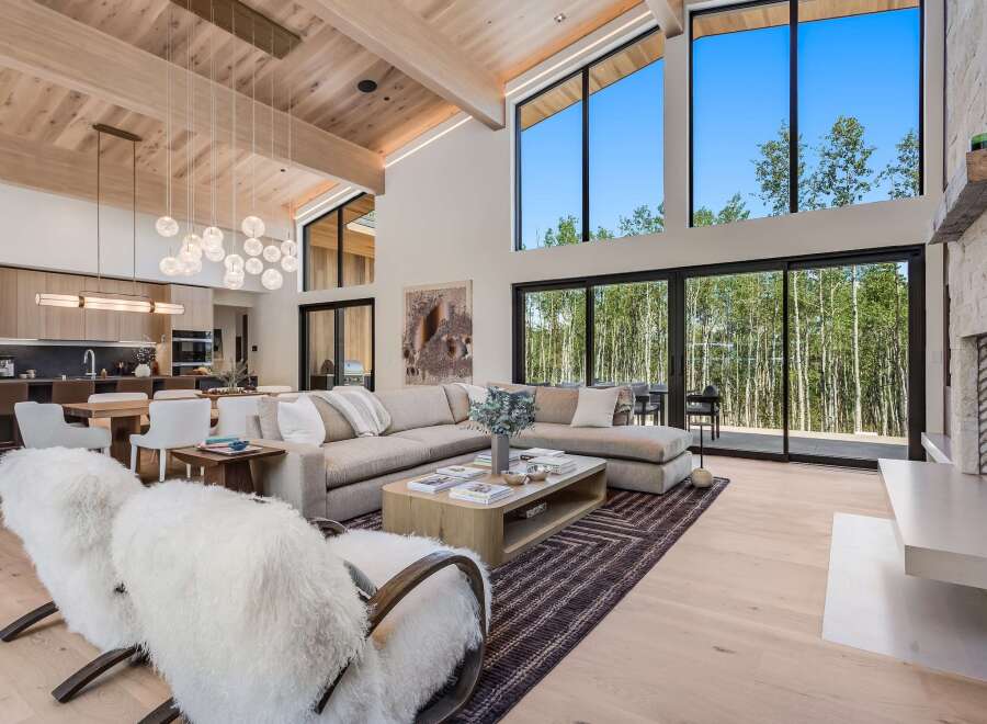 Experience luxury mountain living in this stunning home featuring a spacious open-concept living area with soaring ceilings and a wall of windows showcasing breathtaking forest views.