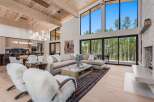 Experience luxury mountain living in this stunning home featuring a spacious open-concept living area with soaring ceilings and a wall of windows showcasing breathtaking forest views.
