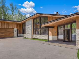 Experience modern luxury in this stunning home featuring natural wood siding and stone accents.
