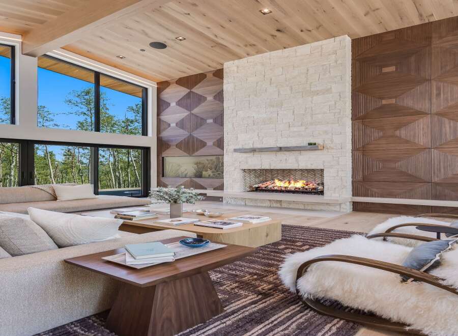 Experience luxury living in this stunning great room, featuring a soaring ceiling with natural wood beams and a magnificent stone fireplace.