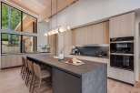 Experience modern luxury in this stunning kitchen, featuring sleek, light wood cabinetry and a spacious dark stone island perfect for entertaining.