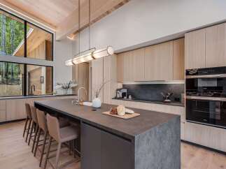 Experience modern luxury in this stunning kitchen, featuring sleek, light wood cabinetry and a spacious dark stone island perfect for entertaining.