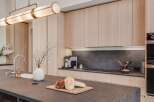 Experience modern luxury in this stunning kitchen, featuring sleek, light wood cabinetry and a sophisticated dark stone countertop.