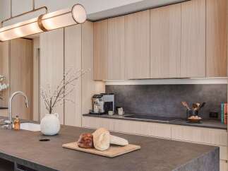 Experience modern luxury in this stunning kitchen, featuring sleek, light wood cabinetry and a sophisticated dark stone countertop.