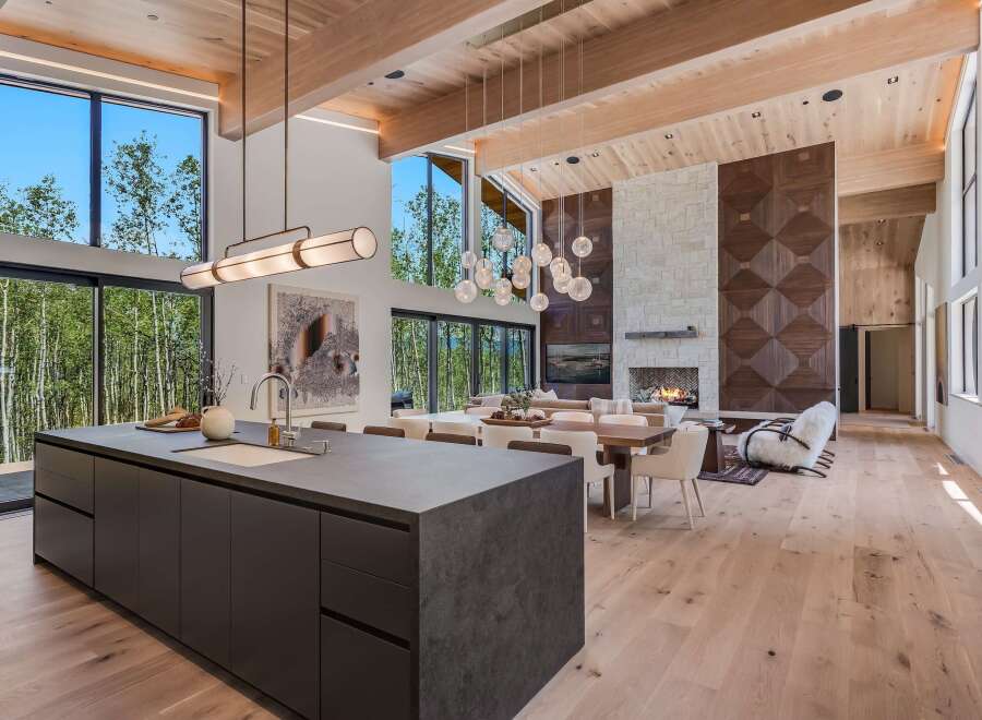 Experience luxury living in this stunning modern home featuring an open-concept living space with soaring ceilings and expansive windows that frame breathtaking forest views.