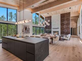 Experience luxury living in this stunning modern home featuring an open-concept living space with soaring ceilings and expansive windows that frame breathtaking forest views.