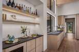 This modern home bar features sleek wooden cabinetry and floating shelves stocked with a variety of spirits and glassware.