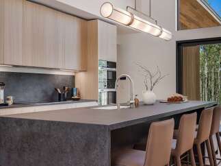 Experience modern luxury in this stunning kitchen, featuring sleek light wood cabinetry and a dramatic dark stone island.