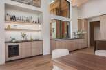 Experience sophisticated entertaining in this modern home featuring a sleek wet bar with a wine fridge and ample shelving for spirits.