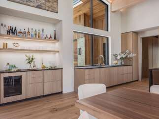 Experience sophisticated entertaining in this modern home featuring a sleek wet bar with a wine fridge and ample shelving for spirits.