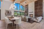 Experience luxury living in this stunning open-concept great room, featuring a soaring ceiling with exposed wood beams and a magnificent floor-to-ceiling stone fireplace.
