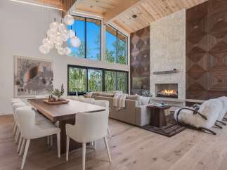 Experience luxury living in this stunning open-concept great room, featuring a soaring ceiling with exposed wood beams and a magnificent floor-to-ceiling stone fireplace.