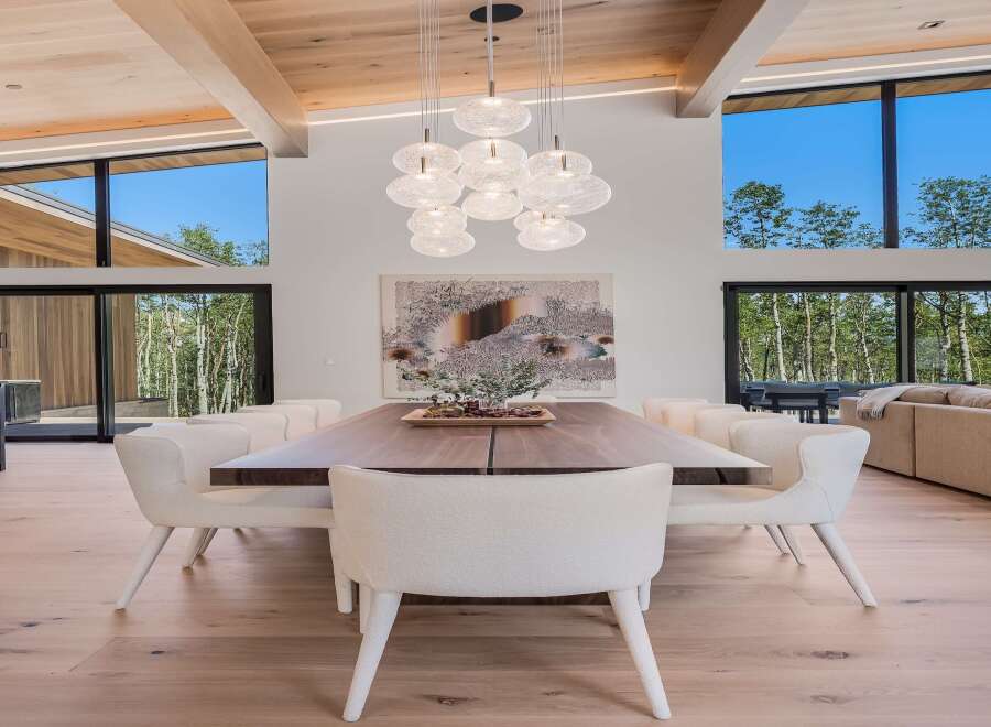 Experience modern luxury in this stunning dining area, featuring a grand walnut dining table surrounded by plush, boucle upholstered chairs.