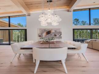Experience modern luxury in this stunning dining area, featuring a grand walnut dining table surrounded by plush, boucle upholstered chairs.