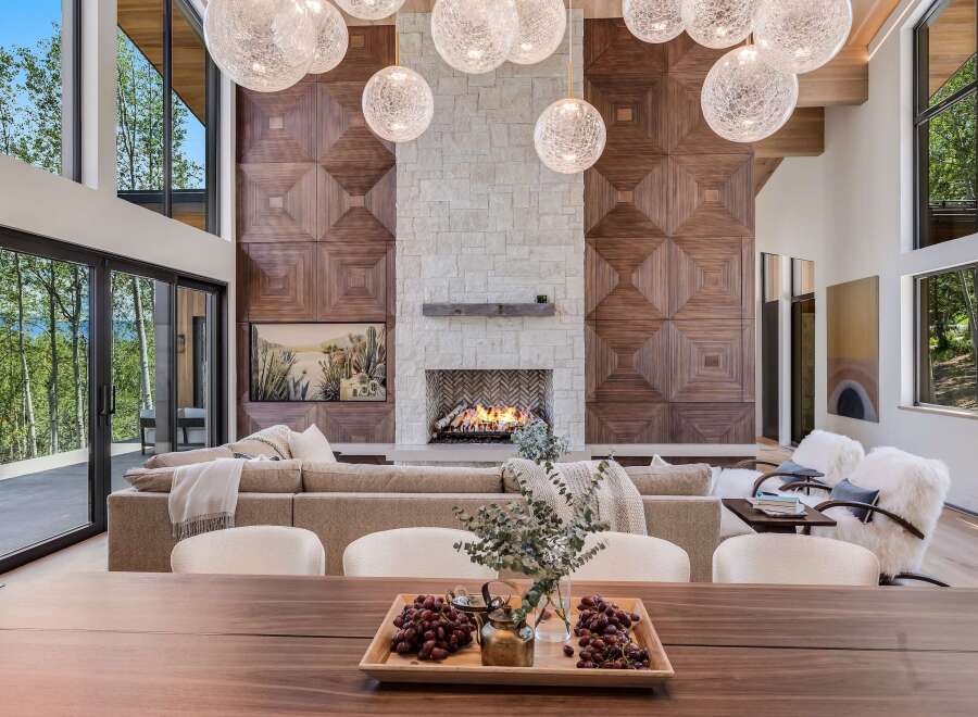 Experience luxury living in this stunning modern home, featuring a grand living room with a striking wood-paneled accent wall and a cozy stone fireplace.