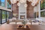 Experience luxury living in this stunning modern home, featuring a grand living room with a striking wood-paneled accent wall and a cozy stone fireplace.