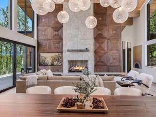 Experience luxury living in this stunning modern home, featuring a grand living room with a striking wood-paneled accent wall and a cozy stone fireplace.