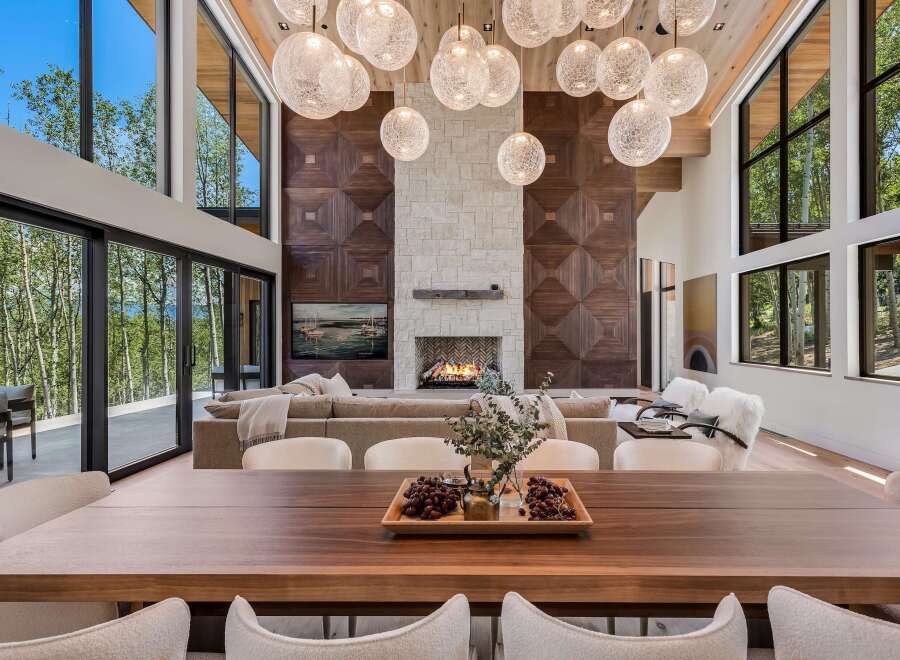 Experience luxury living in this stunning modern home, featuring a grand living area with a soaring ceiling and a magnificent stone fireplace.