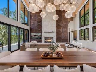 Experience luxury living in this stunning modern home, featuring a grand living area with a soaring ceiling and a magnificent stone fireplace.