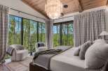 Experience luxury mountain living in this stunning bedroom, featuring floor-to-ceiling windows that offer breathtaking views of the surrounding aspen forest.