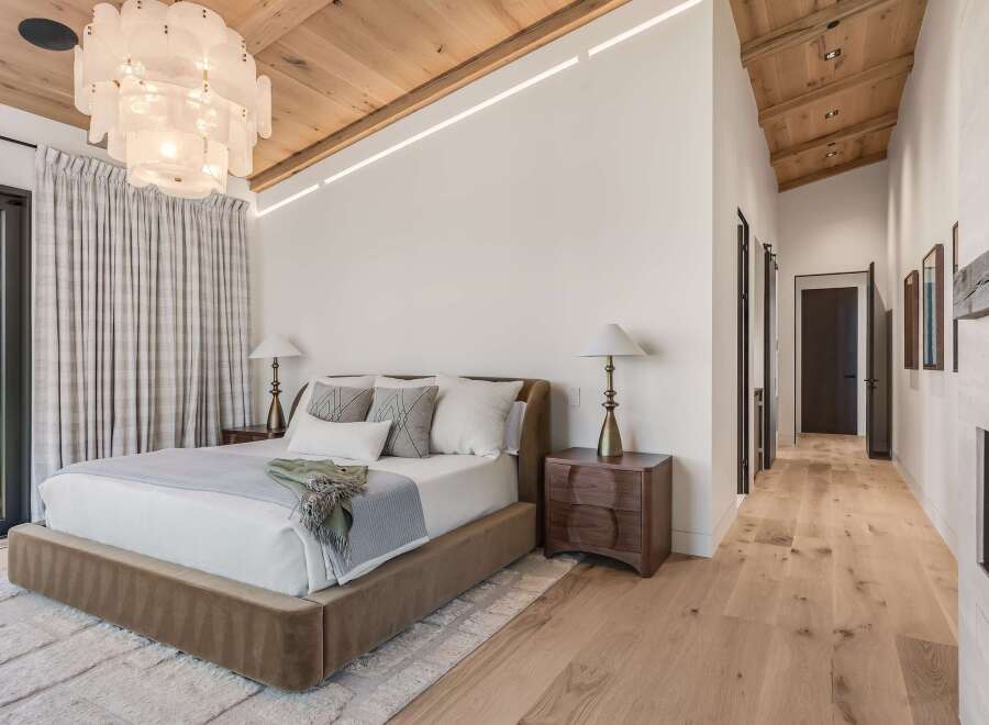 Experience luxury in this master bedroom featuring a plush bed, elegant bedside tables, and a stunning statement chandelier.