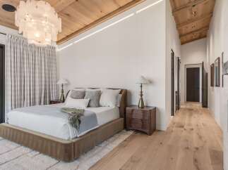 Experience luxury in this master bedroom featuring a plush bed, elegant bedside tables, and a stunning statement chandelier.