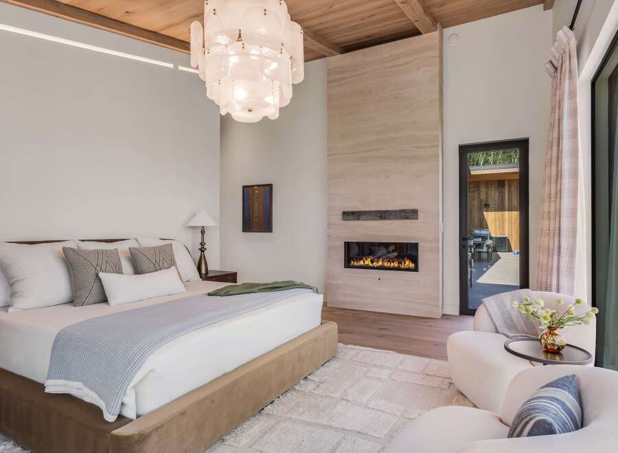 Experience luxury living in this master bedroom, featuring a modern gas fireplace set against a stunning travertine accent wall.