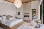 Experience luxury living in this master bedroom, featuring a modern gas fireplace set against a stunning travertine accent wall.