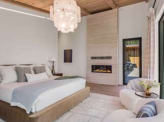 Experience luxury living in this master bedroom, featuring a modern gas fireplace set against a stunning travertine accent wall.