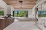 Experience luxury in this modern bathroom featuring a freestanding soaking tub with a stunning forest view.