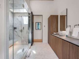 Experience modern luxury in this stunning bathroom featuring a spacious marble shower with multiple showerheads and a built-in bench.