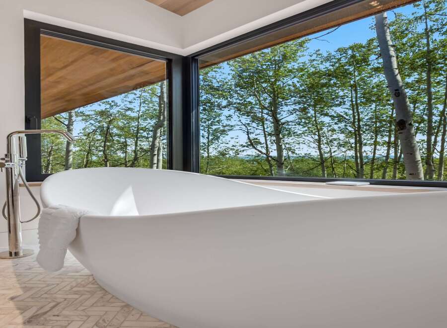 Experience ultimate relaxation in this luxurious bathroom featuring a freestanding soaking tub with a stunning forest view.