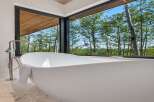 Experience ultimate relaxation in this luxurious bathroom featuring a freestanding soaking tub with a stunning forest view.