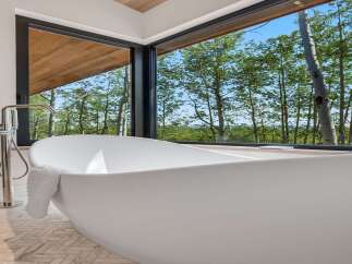 Experience ultimate relaxation in this luxurious bathroom featuring a freestanding soaking tub with a stunning forest view.