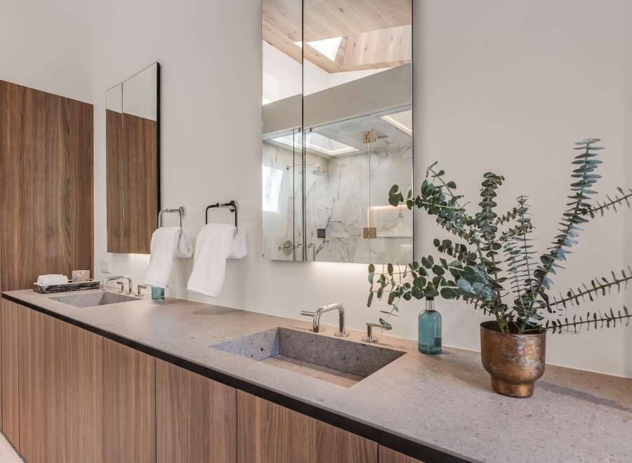 Experience modern luxury in this stunning bathroom featuring a dual vanity with sleek concrete sinks and warm wood cabinetry.