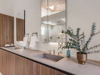 Experience modern luxury in this stunning bathroom featuring a dual vanity with sleek concrete sinks and warm wood cabinetry.