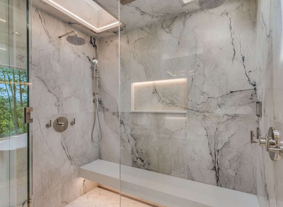 Experience ultimate relaxation in this luxurious marble shower, featuring a built-in bench and multiple shower heads for a spa-like experience.