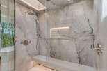 Experience ultimate relaxation in this luxurious marble shower, featuring a built-in bench and multiple shower heads for a spa-like experience.