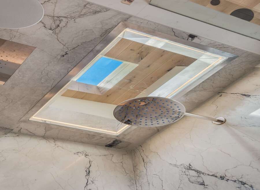 Experience luxury in this modern bathroom featuring a stunning marble design and a unique skylight.