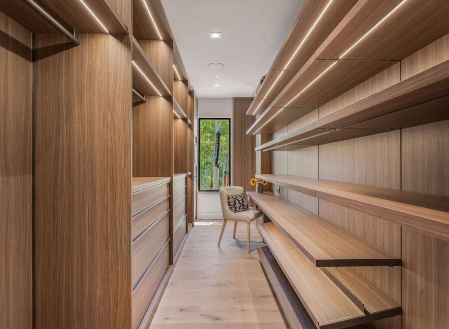 Experience unparalleled organization in this custom walk-in closet, featuring rich wood cabinetry and ample shelving.