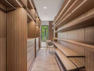 Experience unparalleled organization in this custom walk-in closet, featuring rich wood cabinetry and ample shelving.