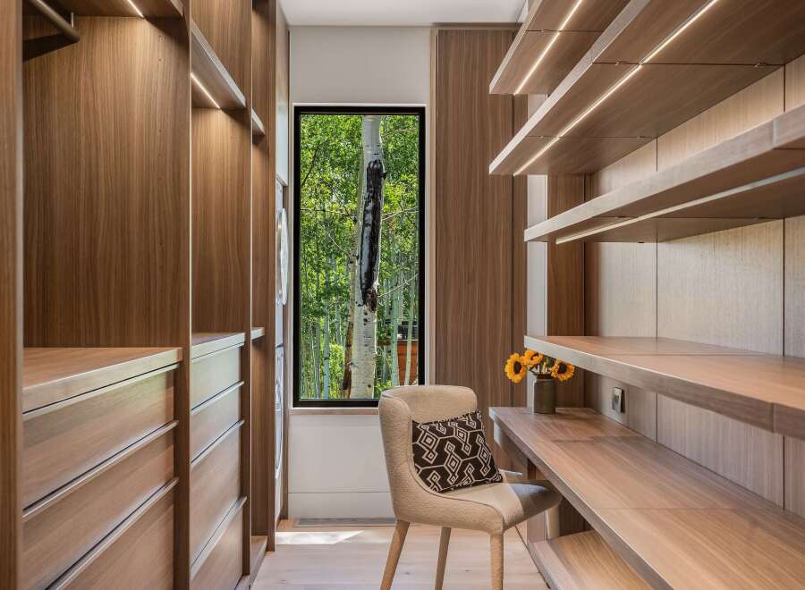 Experience luxurious organization in this modern walk-in closet, featuring rich walnut cabinetry and integrated LED lighting.