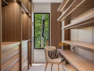 Experience luxurious organization in this modern walk-in closet, featuring rich walnut cabinetry and integrated LED lighting.