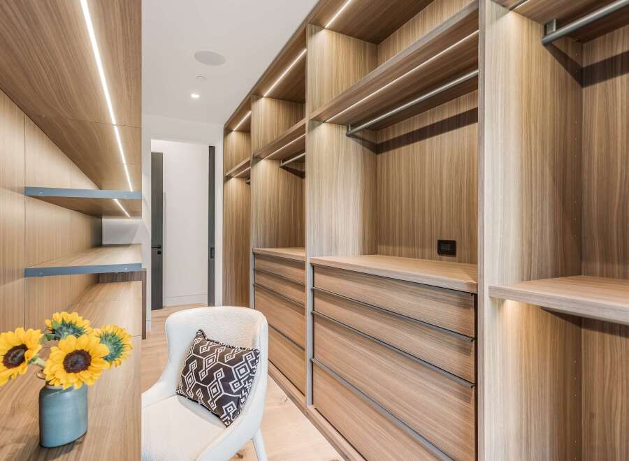 Step into this luxurious walk-in closet, featuring custom wood cabinetry with integrated LED lighting for a sophisticated ambiance.